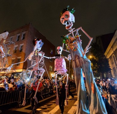 Large skeleton dolls being carried down the street during the Halloween Parade